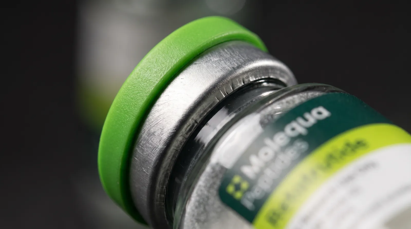 Macro del tapón verde y el precinto de aluminio de un vial de péptido de investigación